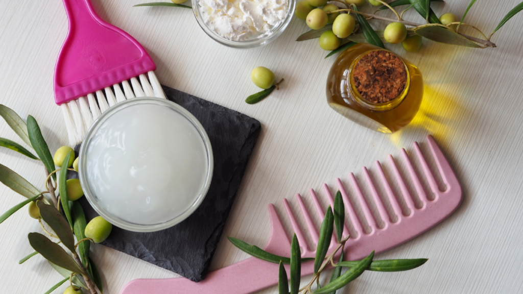 Ingredientes naturais para um creme anti-idade caseiro, como azeite, manteiga vegetal e óleo essencial, dispostos ao lado de um pente e pincel de aplicação, representando a simplicidade e eficácia dos cuidados com a pele utilizando receitas caseiras e orgânicas