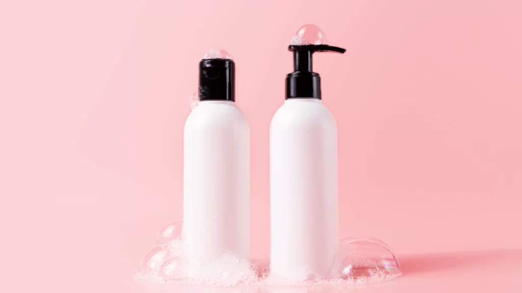 Frascos de shampoo caseiro, com espuma ao redor, destacando uma opção natural e sustentável para o cuidado capilar, ideal para fortalecer os fios de forma saudável.