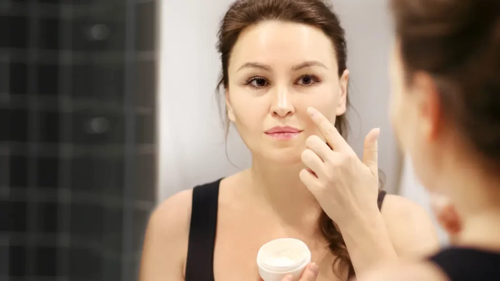 Mulher aplicando creme em sua rotina de skincare anti-idade, cuidando da pele para combater os sinais de envelhecimento.