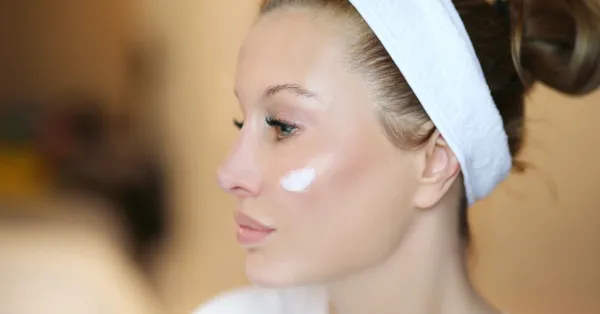 Mulher aplicando creme facial na pele como parte de sua rotina de skincare anti-idade.